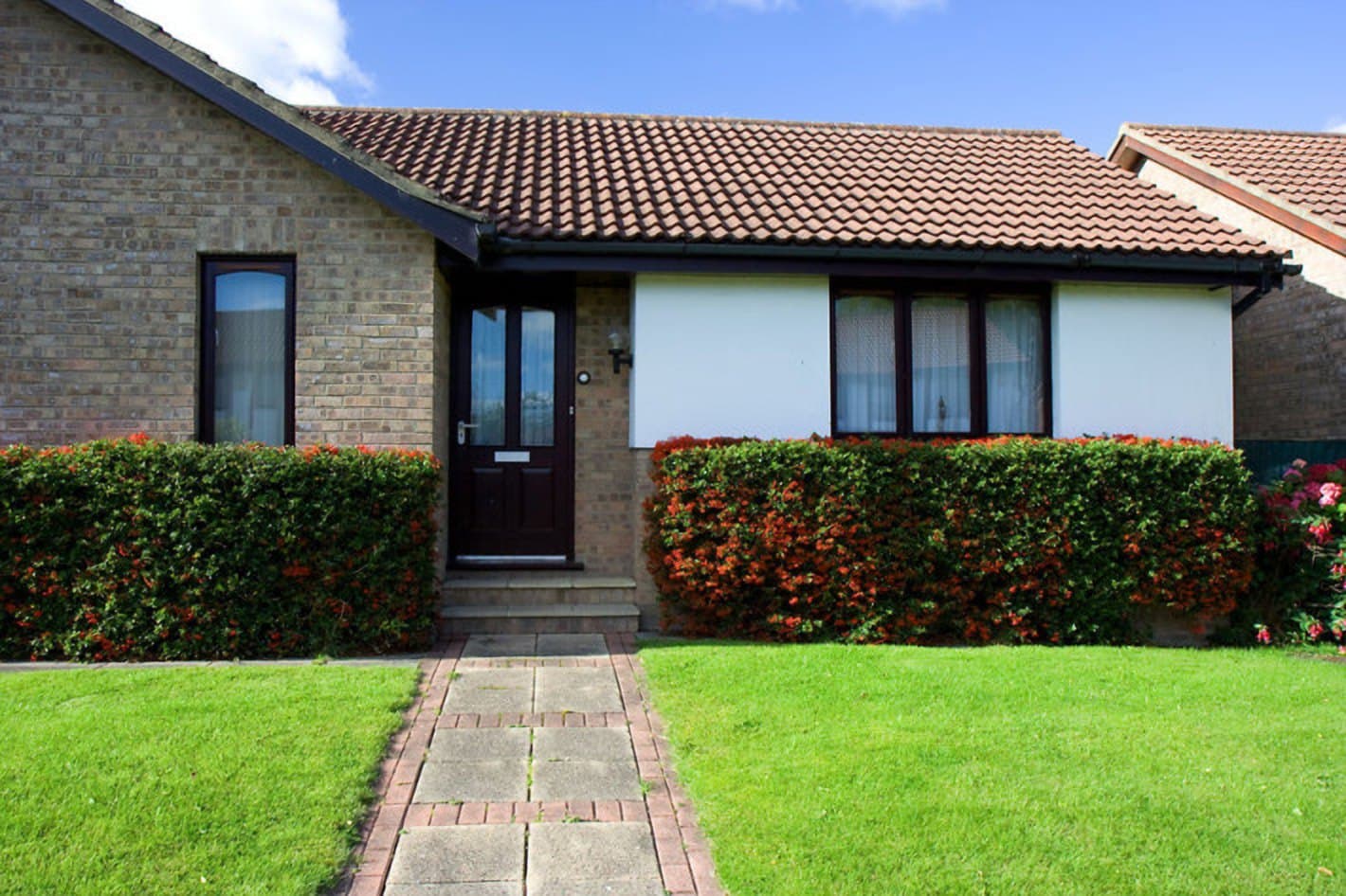 Detached house with a lawn and a flowering hedge, illustrating real estate law